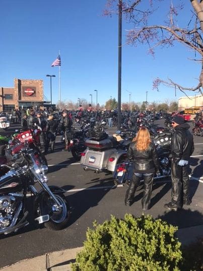 A group of people standing around motorcycles in the street.