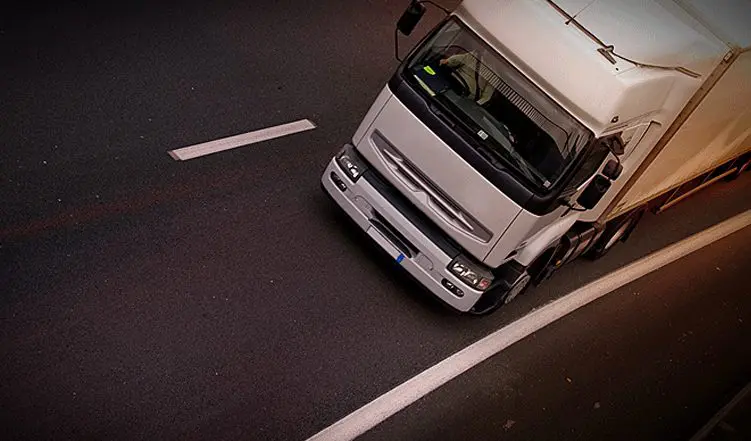 A truck is driving down the street in traffic.